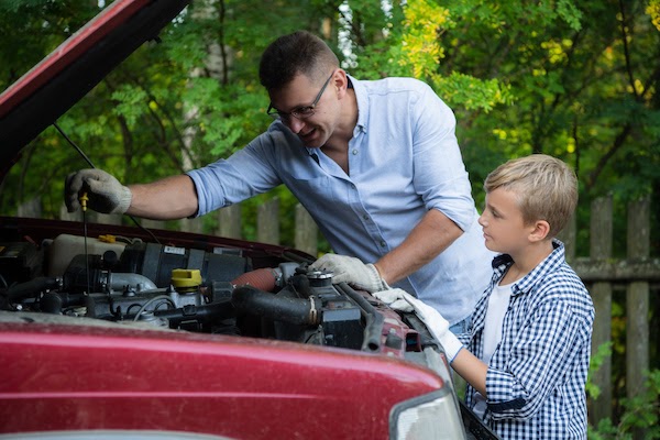 Father and son working on car outside