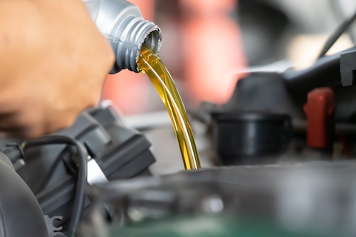 Pouring synthetic oil to car engine. Fresh oil poured during an oil change to a car.