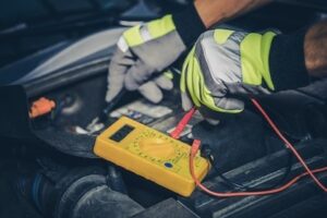 auto mechanic measures car battery