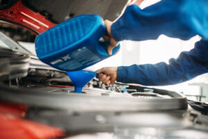 auto mechanic pouring oil into car engine