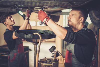 two auto mechanics performing an oil change service
