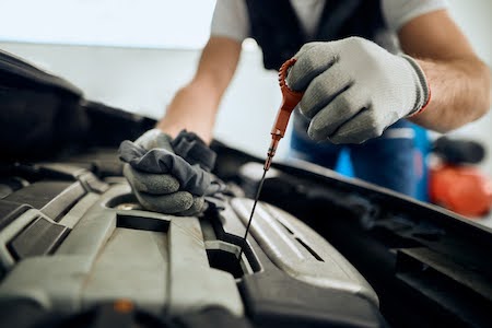 car mechanic checking motor oil